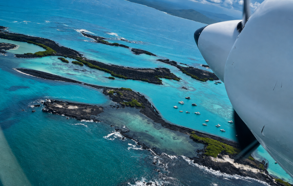 Aerial view of turquoise waters and volcanic coastline during an inter-island flight in the Galapagos Islands.