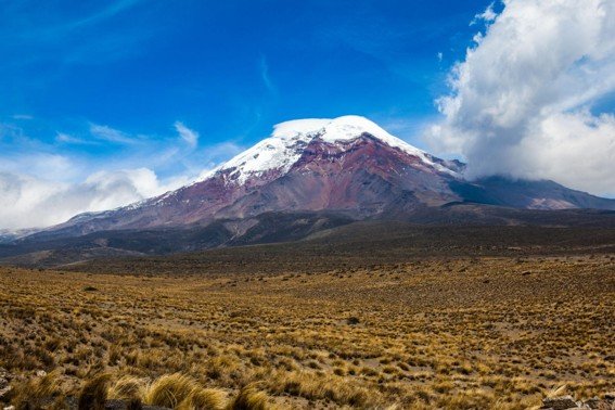 Chimborazo volcano rising above the high-altitude landscape of the Ecuadorian Andes under a clear blue sky.