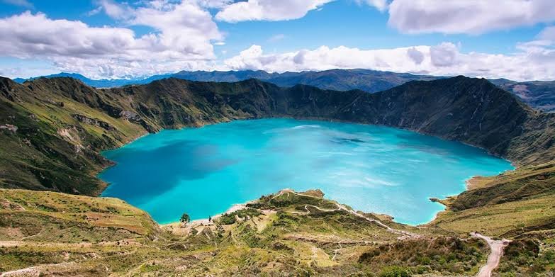 Turquoise waters of Quilotoa crater lake surrounded by volcanic mountains in the Ecuadorian Andes.